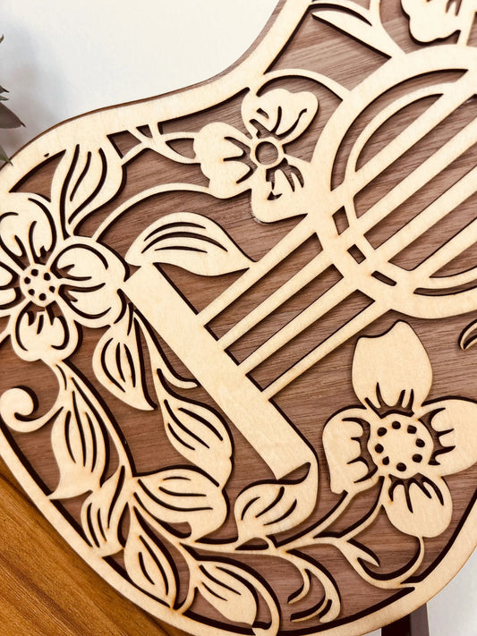 Détail de la Guitare Décorative en Bois avec Motifs Floraux de Le Bois Elégant, montrant les motifs floraux sculptés. Ce design unique en GUITARE et en BOIS apporte une touche artistique à toute DECORATION, un choix inspirant pour les amateurs de MUSIQUE.
