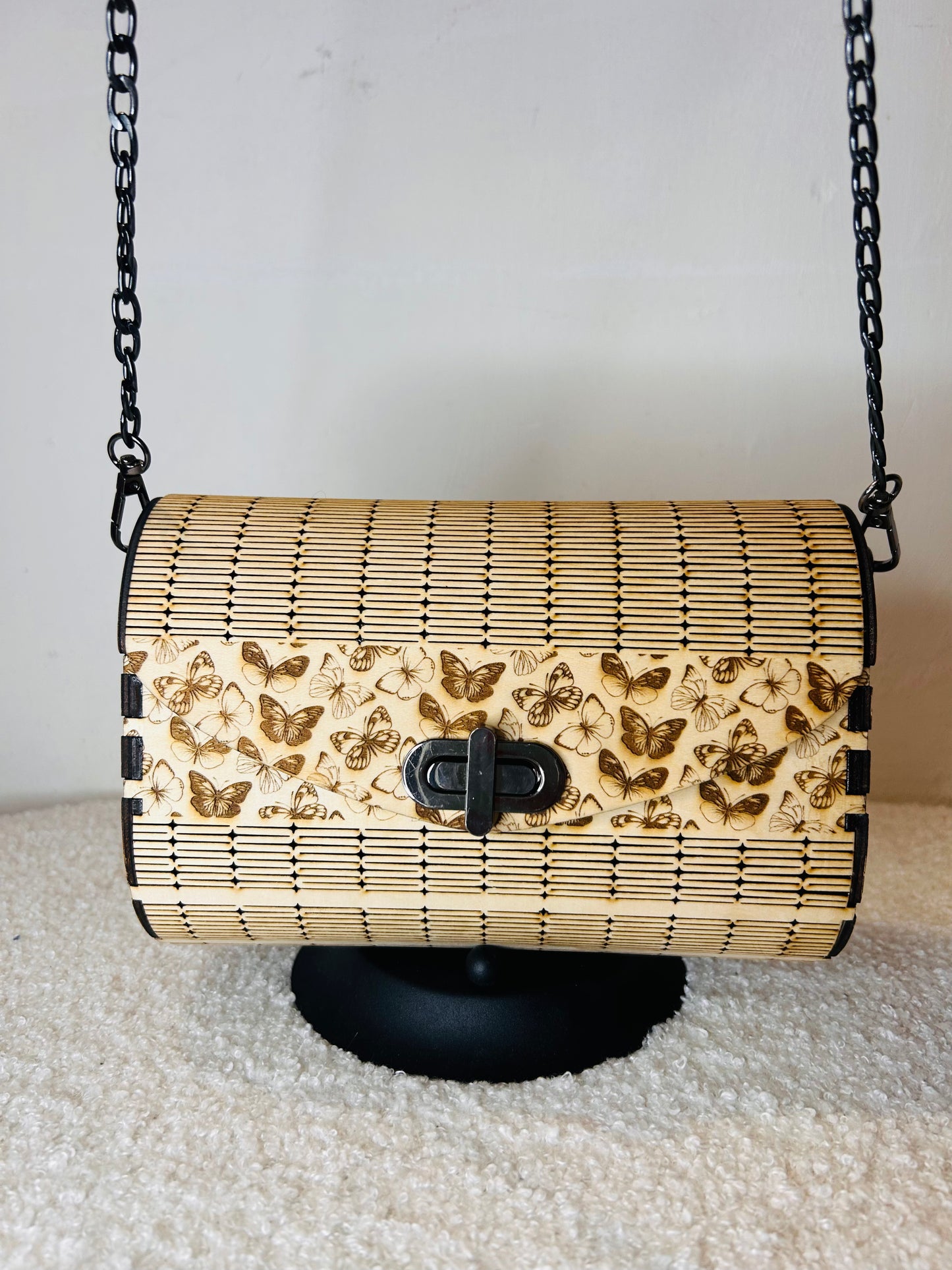 Sac en bois Papillon Élégant de Le Bois Elégant, affiché sur un support avec sa chaîne en métal noir, parfait pour les soirées élégantes.