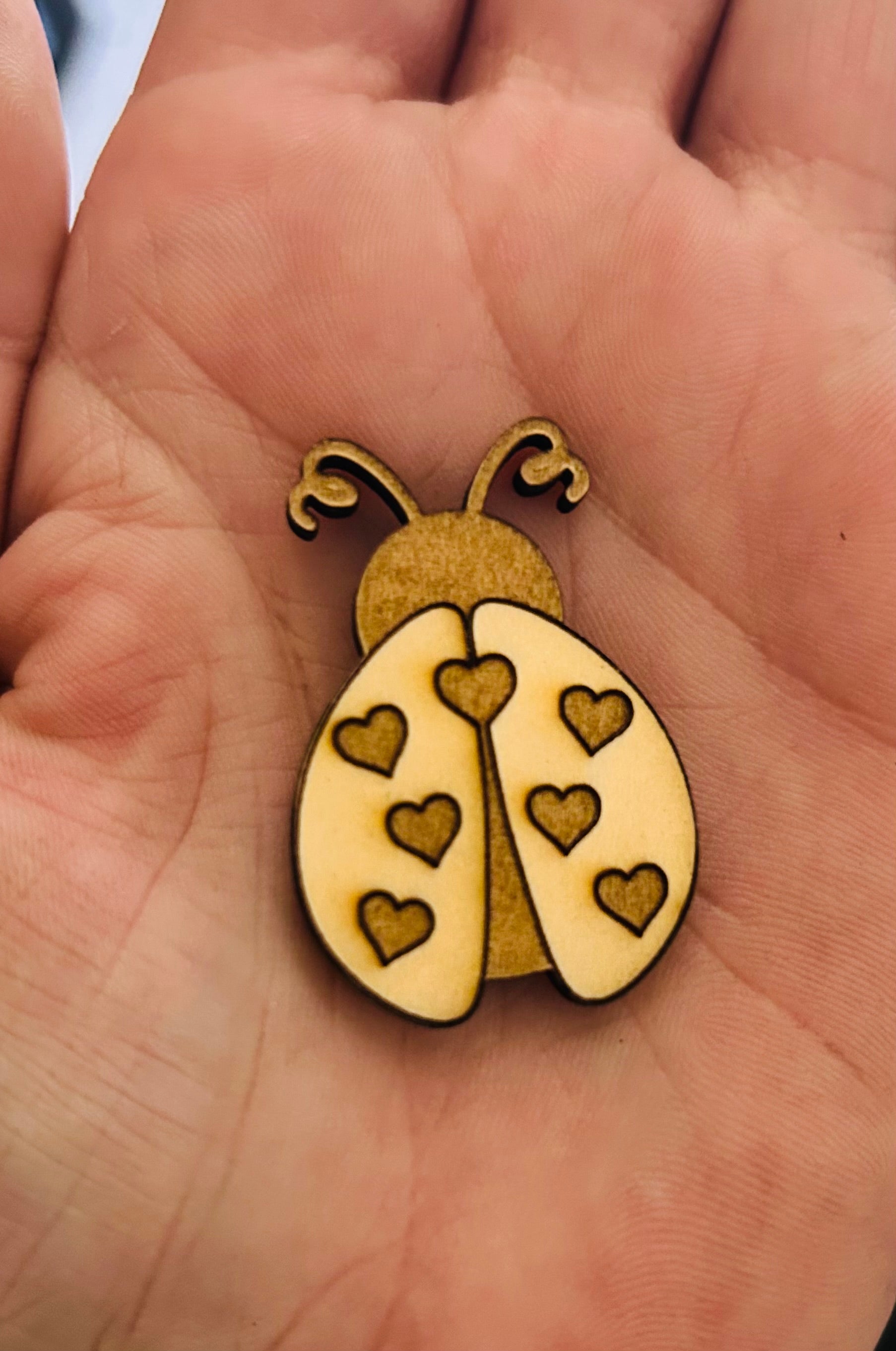 Détail d'une coccinelle en bois gravée dans la main, illustrant la carte porte-bonheur coccinelle de Le Bois Elégant, parfaite pour offrir un peu de chance à ceux qui en ont besoin.