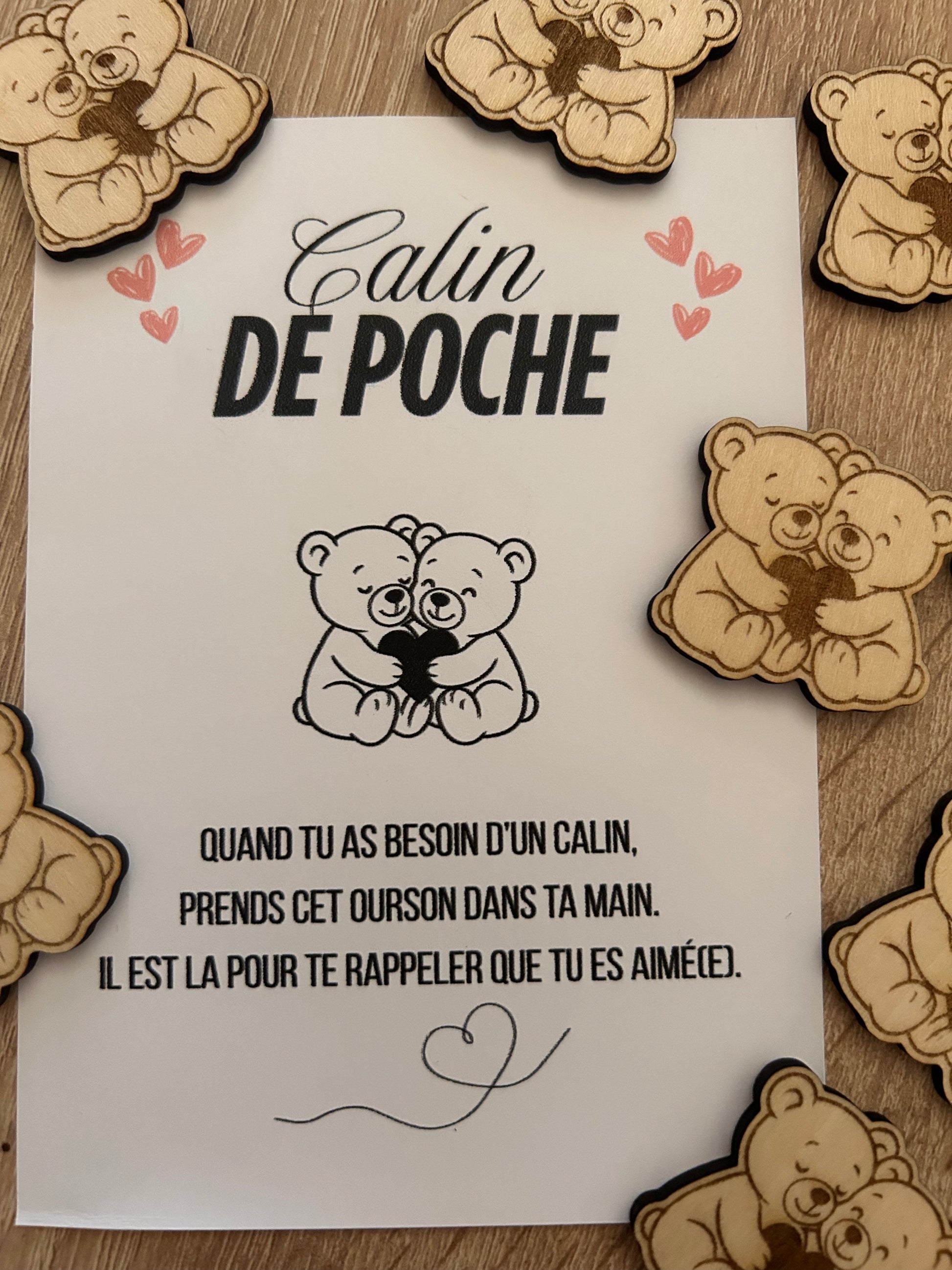 Image de plusieurs oursons du Câlin de Poche de Le Bois Elégant disposés autour d'une carte. Ce doux cadeau symbolise le réconfort et l'amour, parfait à offrir à ceux que vous chérissez. calin de poche, pockethug
