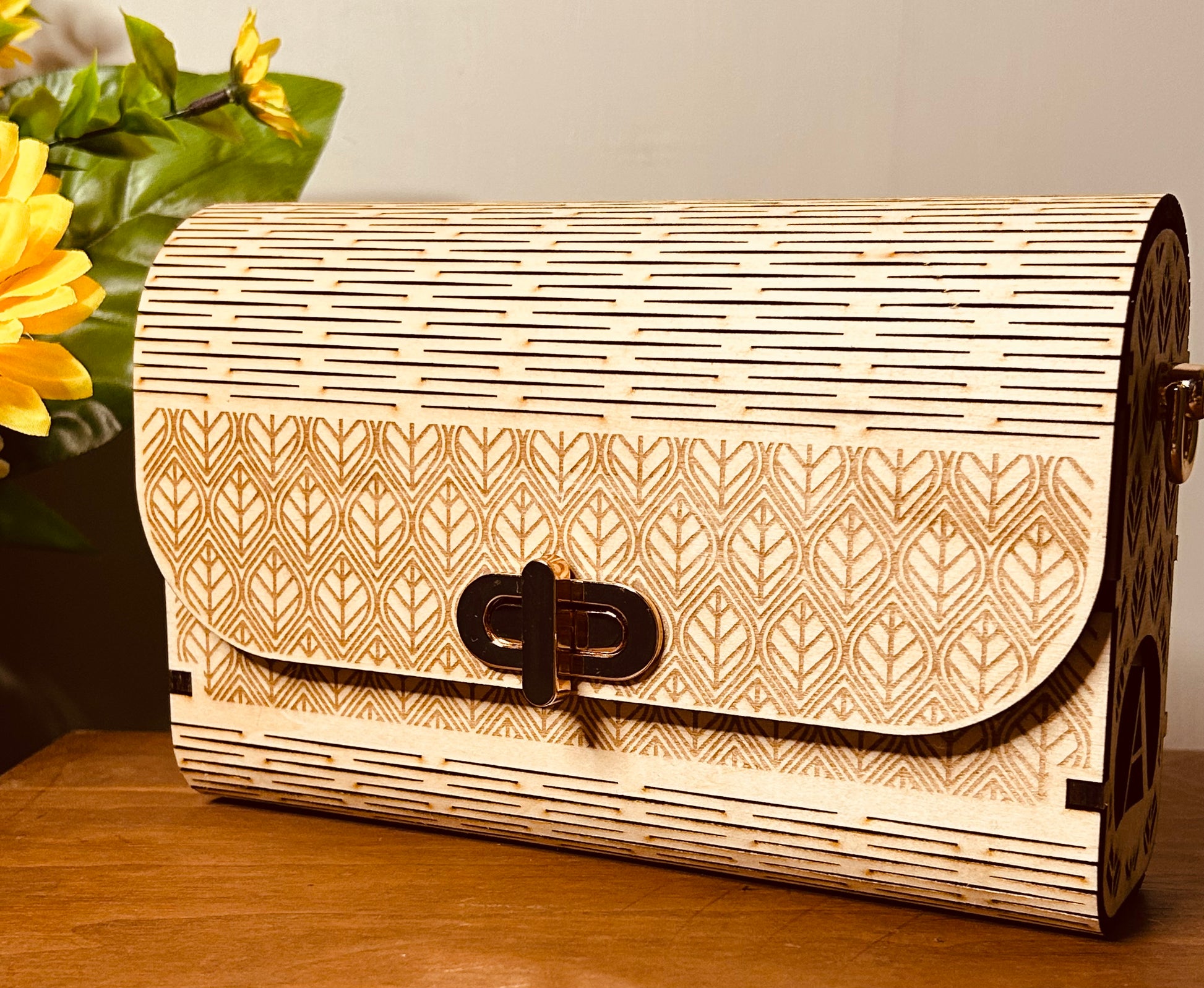 Sac en bois personnalisé Mimi de Le Bois Elégant sur une table, montrant le motif de feuilles et le fermoir élégant.