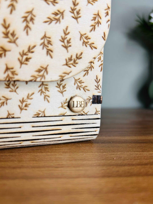 Sac romantique Le Bois Elégant en bois avec détails élégants et fermeture métallique, posé sur une surface en bois.