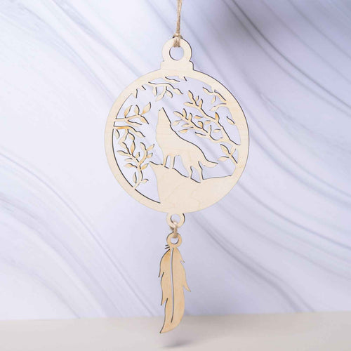 Attrape-rêves en bois de la marque Le Bois Elégant, avec des plumes et perles, suspendu dans un décor naturel.